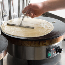 A crêpe being freshly prepared on the griddle